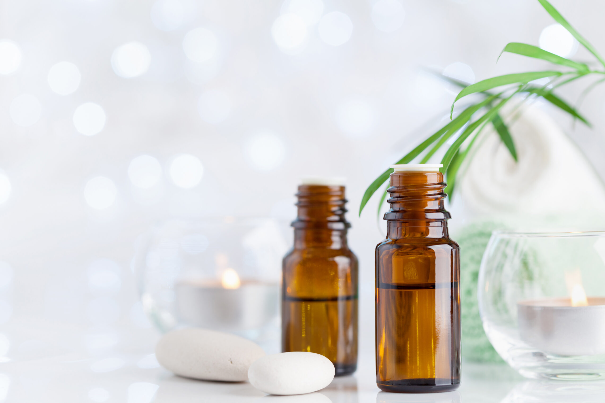 Bottle with essential oil, towel and candles on white table. Spa, aromatherapy, wellness, beauty background.